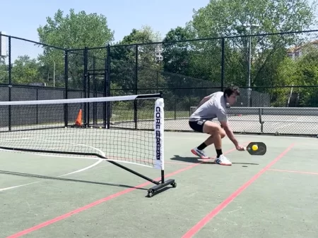 Pickleball player executing the ATP shot around the net post.